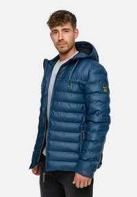 Marineblå dunjakke med hætte, quiltet design, lynlåslukning, sidelommer og grå snore. Letvægts, skinnende materiale.
