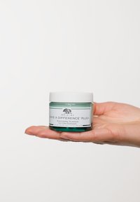Bocal en verre transparent de gel hydratant, de couleur vert clair avec un couvercle blanc, étiqueté "MAKE A DIFFERENCE™ PLUS+" et logo d'arbre décoratif.