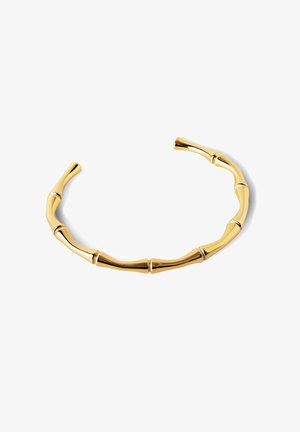 Złota bransoletka o wzorze inspirowanym bambusem, z cylindrycznymi segmentami i gładką, wypolerowaną fakturą. Otwarta na końcach, co ułatwia zakładanie.