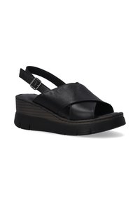 Zwarte lederen slingback sandalen met kruislings banden, open teen, dikke wiggenhak en rubberen zool met diepe groeven voor grip.