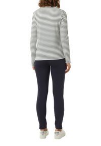 Gestreiftes langärmeliges Oberteil in Hellgrau mit marineblauen Streifen, kombiniert mit engen marineblauen Hosen und weißen Sneakers mit metallischen Akzenten.