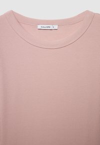 T-shirt rosa chiaro a coste con collo rotondo e maniche corte; presenta un'etichetta con la scritta "CALLIOPE" e la taglia "S" visibile.
