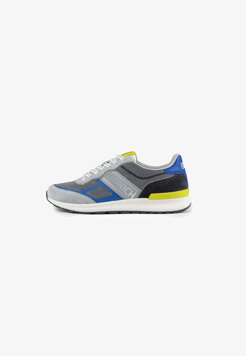 Gray athletic shoe with mesh and suede materials, featuring blue and green accents, patterned side panel, and white midsole.