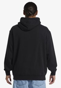 Zwarte hoodie met een losse pasvorm, voorzien van een buidelzak en geribde manchetten. De stof lijkt zacht met een lichte glans.