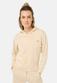 Beige hoodie met een relaxte pasvorm, V-hals ontwerp en lange mouwen. Beschikt over een klein oranje logo aan de linkerkant. Zachte stofstructuur.