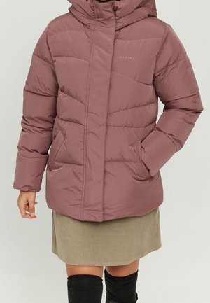 Personne portant une veste matelassée mauve avec capuche, poches avant, associée à une jupe beige et des chaussettes hautes noires.