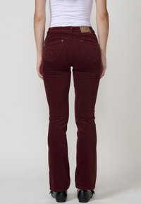 Bordeaux corduroy flared jeans met achterzakken en een merkembleem op de tailleband, die een getailleerde silhouet en gestructureerde stof laten zien.