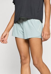 Világoskék sportnadrág sima textúrával, finom mintázattal és az oldalon három függőleges világos csíkkal.