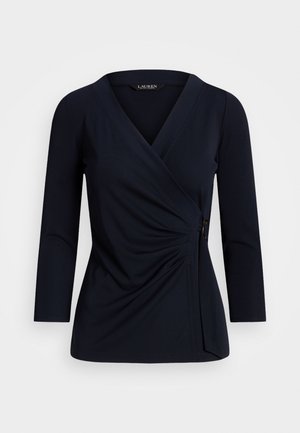 Granatowy długi rękaw bluzki kopertowej z dekoltem w serek, bocznym detalem z klamrą i subtelnym drapowaniem w talii.
