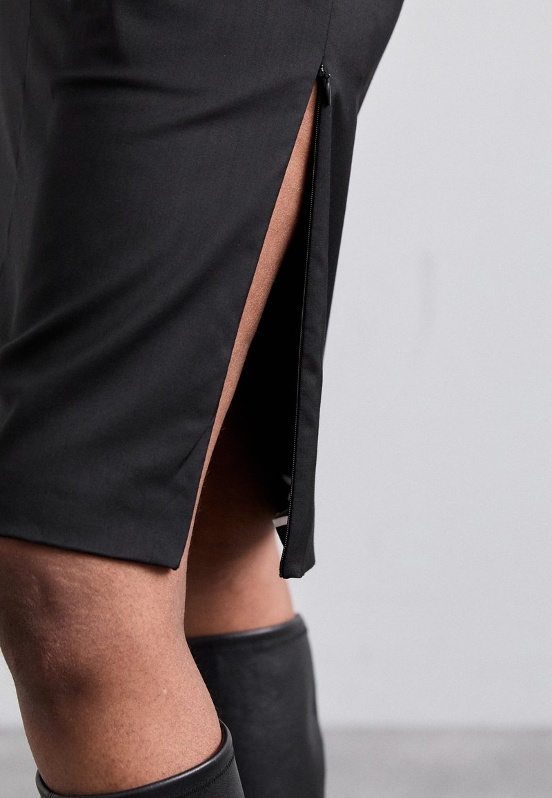Black skirt with a side zipper and slit, smooth fabric, fitted design, highlighting a knee-length silhouette and sleek texture.