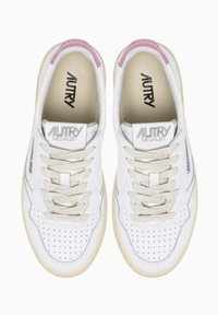 Sneakers in pelle bianca con punta traforata, lacci color crema e dettagli rosa sul tallone. Presentano il marchio "AUTRY" sulla linguetta.
