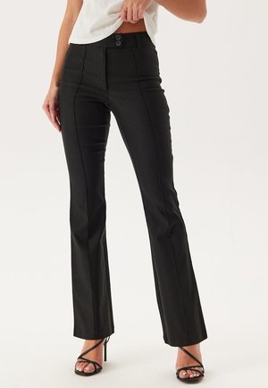 Pantalons évasés noirs avec une texture lisse, taille haute, deux boutons en haut et des détails cousus sur le devant.