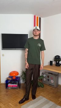 Πράσινο κοντομάνικο μπλουζάκι με λευκό λογότυπο, καφέ κομμένα παντελόνια και μπορντό παπούτσια. Τα αξεσουάρ περιλαμβάνουν ένα κρεμ καπέλο. Απλός, μοντέρνος σχεδιασμός.