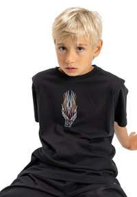 Camiseta de algodón negra con un gráfico de llama prominente en rojo, naranja y blanco. Manga corta y corte relajado.