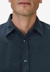 Marinblå knapparskjorta med mjuk textur, spridd krage och två knappar vid halsen. Har en skräddarsydd passform och rena linjer.