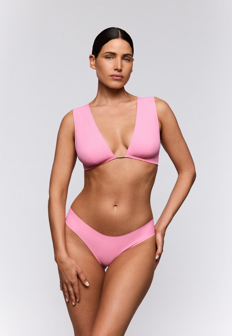 Ensemble bikini rose comprenant un haut à décolleté plongeant avec de larges bretelles et un bas minimaliste. Texture lisse, design sans coutures et sans motifs.