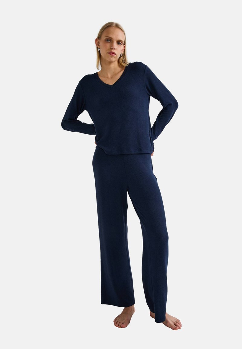 Ensemble de salon bleu marine comprenant un haut à manches longues en V et un pantalon large assorti, fabriqué à partir d'un tissu doux au toucher lisse.
