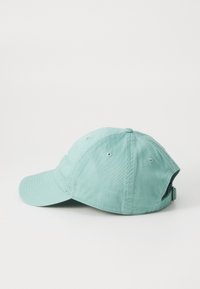 Casquette de baseball en teal clair en coton. Elle possède un visière incurvé, une sangle ajustable à l'arrière et six œillets de ventilation.