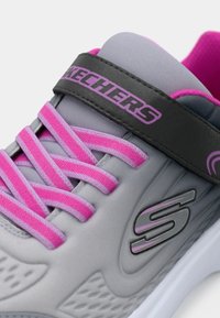 Kerged jooksujalats hallis koos roosa aktsentidega. Omab elastseid paelu, musta rihma logoga ja tekstuurset külgdetaili.