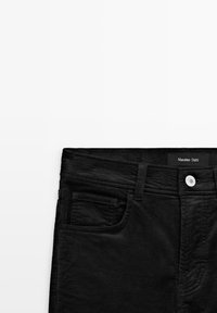 Pantaloni in corda nera con design classico, tasche frontali e bottone bianco. L'etichetta riporta "Massimo Dutti." Tessuto a coste testurizzato.