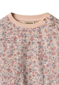 Top a maniche lunghe con motivo floreale in rosa chiaro, decorato con fiori viola e rossi. Presenta un colletto a coste e due bottoni decorativi sulla spalla.