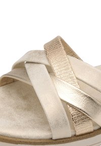 Sandaletter med remme i metallisk guld og creme, med krydset design, teksturerede metalliske detaljer og en flad, polstret sål.