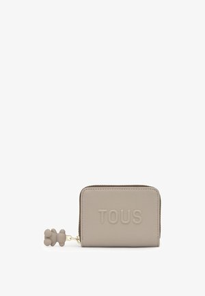 Portafoglio rettangolare beige con testo "TOUS" in rilievo, pelle testurizzata e tiretto della cerniera a forma di orsacchiotto coordinato.
