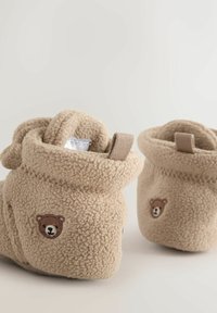 Beżowe buciki z polaru z podwiniętym mankietem, z małym haftem misia po boku i teksturowaną powierzchnią. Miękki i ciepły design.