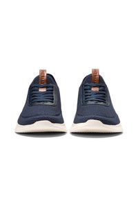 Námořnické pletené tenisky s texturovaným povrchem, světlým béžovým podešvem a hnědým koženým poutkem na patě. Mají šněrování na přední straně.