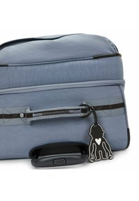 Blauer Weichschalenkoffer mit strukturiertem Oberflächendesign, schwarzen Reißverschlüssen und detaillierten Nähten. Verfügt über einen schwarzen Kunststoffgriff und einen Affenschlüsselanhänger.