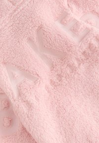 Tessuto in pile rosa morbido con lettere in rilievo che formano la parola "DKNY" in un motivo ripetuto.