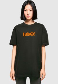 Tricou negru din bumbac cu croială oversized, având o grafică portocalie cu două dovleci de Halloween și cuvântul "Boo!" impriminat deasupra acestora.