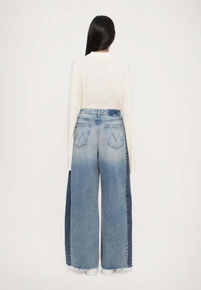 Jeans a gamba larga con gradiente di denim blu chiaro a scuro, pannelli laterali a contrasto e orlo sfibrato. Abbinato a un maglione a maniche lunghe con coste.
