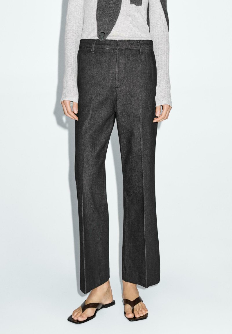 Wide-leg pants made of dark denim, featuring a high waist, straight silhouette, and contrasting white stitching along the seams.