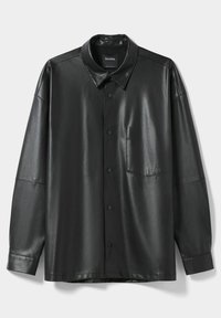 Camisa de imitación cuero negra con un cierre de botones en la parte delantera, cuello puntiagudo, mangas largas y un bolsillo en el pecho. Textura suave y corte holgado.