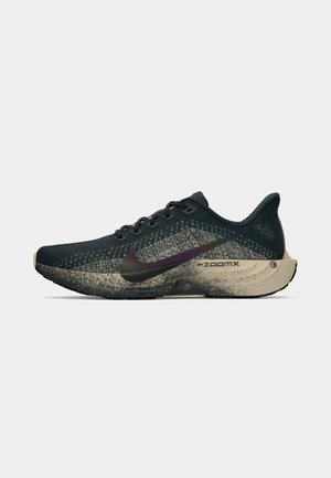 Melns Nike ZoomX skriešanas apavu modelis ar beigu pārklājumu un varavīksnes krāsas Swoosh logo uz baltas fona.