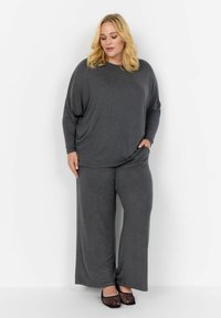 Grå loungekläder set med en löst sittande topp med sänkt axlar och vida byxor. Mjuk textur, minimalistisk design och två sidfickor.