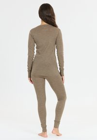 Brun långärmad topp och åtsittande byxor gjorda av ett strukturerat, stretchigt material. Har ribbade manschetter och en rundad sidsöm för komfort.