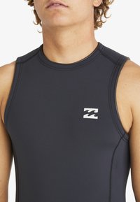 Traje de neopreno sin mangas en azul marino oscuro con costuras planas y un logo de ola blanca en el lado izquierdo del pecho. Material suave y elástico.