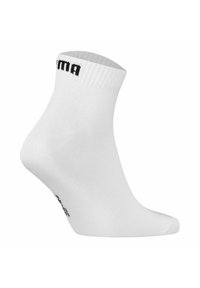 Vit ankelsocka tillverkad av elastiskt material, ribbat manschett, med en svart logotyp tryckt på sidan. Slät textur, standard sockform.