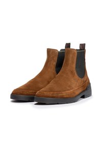 Bottes Chelsea en suede marron avec des panneaux latéraux élastiques, un bout rond et une semelle en caoutchouc noir dotée d'un fond texturé pour une meilleure adhérence.