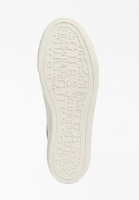 Bílá gumová podešev obuvi s reliéfním vzorem loga "GUESS", zaoblenými okraji a texturovaným povrchem pro lepší grip. Hladké boky bez dalších akcentů.