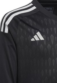 T-shirt de sport noir avec un motif en losanges texturé, présentant trois bandes blanches sur les épaules et un logo adidas argenté sur la poitrine.