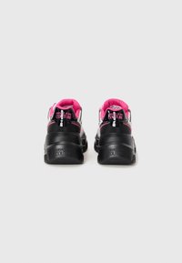 Black, white, and pink Versace Jeans Couture sneakers shown from the back with thick soles and bold branding on heels.