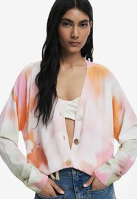 Pastellfarbener Cardigan mit farbverlaufendem Aquarellmuster, featuring einen tiefen V-Ausschnitt, Knopfverschluss und gerippte Bündchen. Getragen über einem cremefarbenen Oberteil.