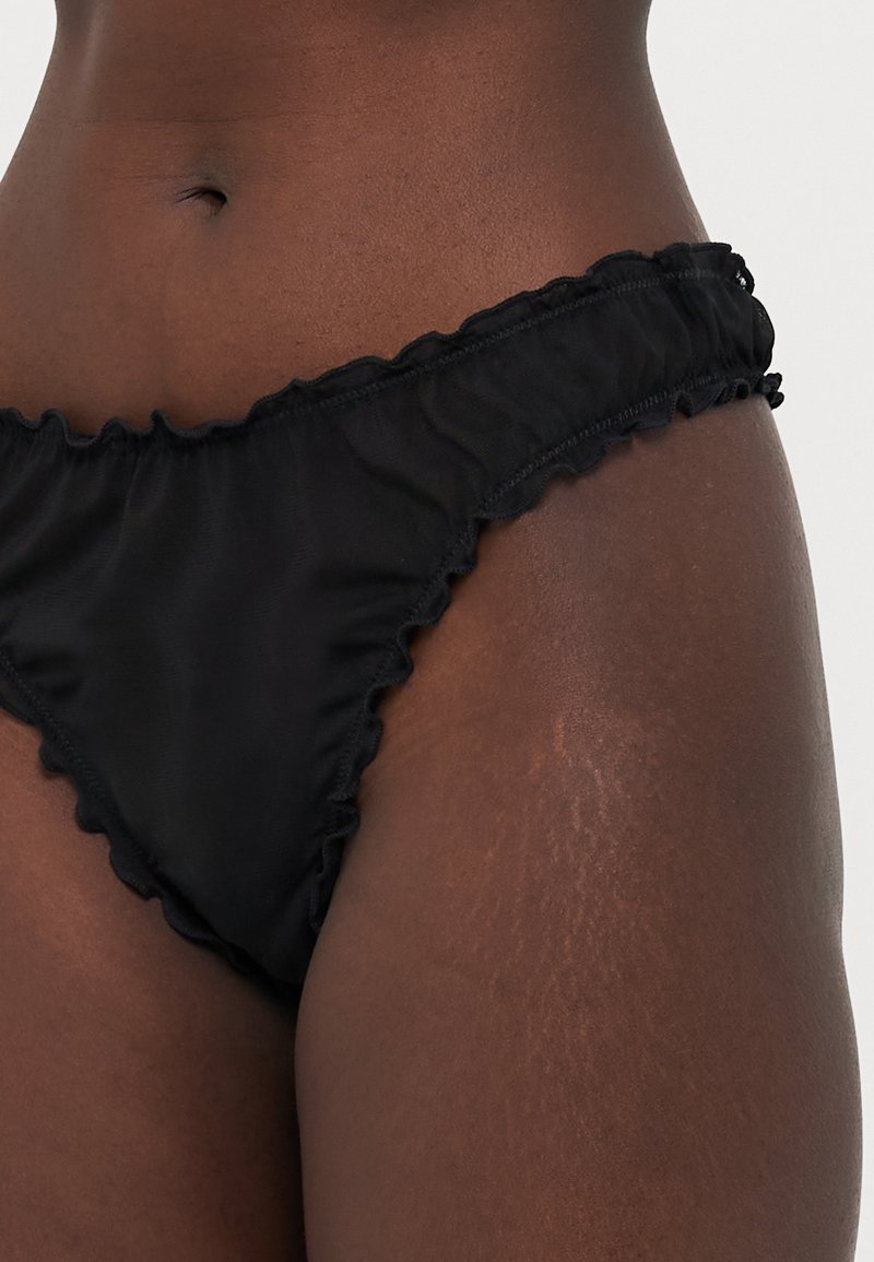 Slip di bikini neri con bordi arricciati, realizzato in tessuto morbido. Presenta un design a vita bassa e dettagli di cucitura sottili.