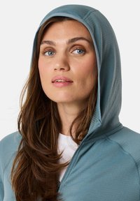 Hooded sweatshirt in soft, light blue fabric. Features a front zipper and a relaxed fit, with visible stitching details and a smooth texture.