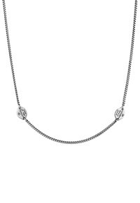 Silverfärgad kedja med ett strukturerat mönster och två runda hängen inskrivna med "Lev i stunden", fästa i var sin ände.