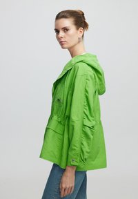 Groene, lichtgewicht hoodiejack met een ontspannen pasvorm, voorzien van twee voorzakken, een taillerende taille en een textuurafwerking.
