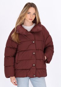 Giacca trapuntata bordeaux con colletto alto, chiusura con bottoni e design trapuntato. Presenta tasche laterali e una vestibilità comoda. Tessuto liscio.